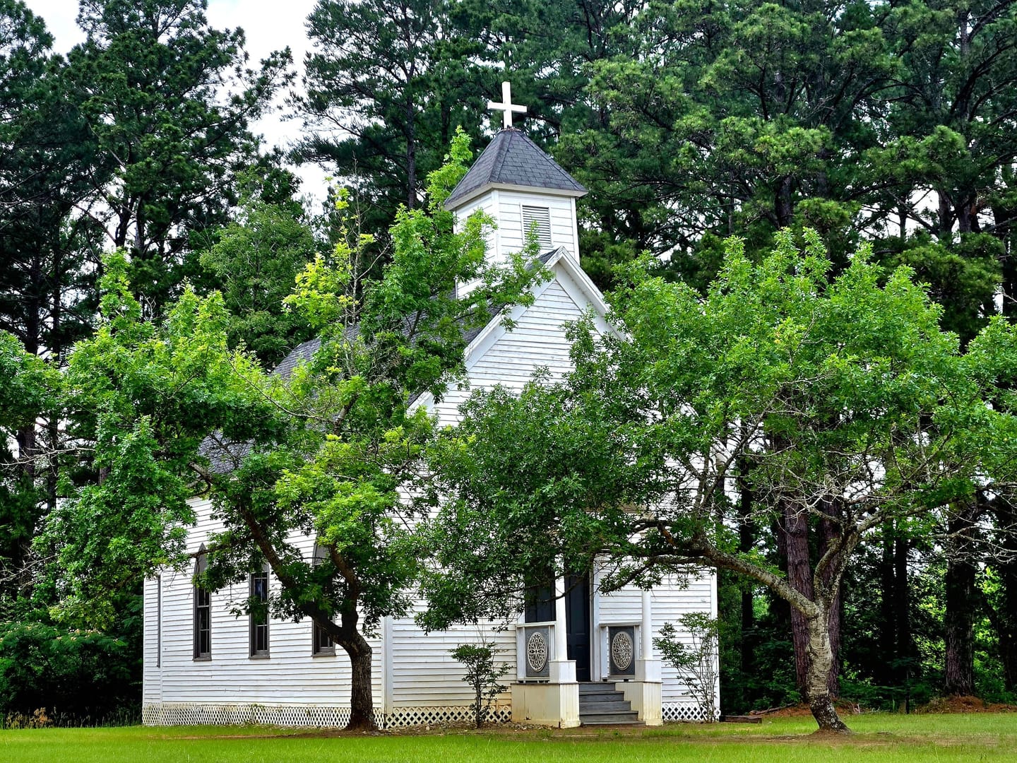 A white wooden church with a steeple among green trees: a licensed stock photo, not a real Example Chapel